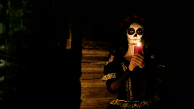 Young-woman-with-scary-skeleton-Halloween-make-up-holding-a-lighted-candle.-HD