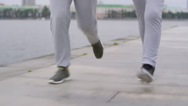 Beine-von-Mutter-und-Sohn-joggen-auf-dem-Riverside-Sidewalk