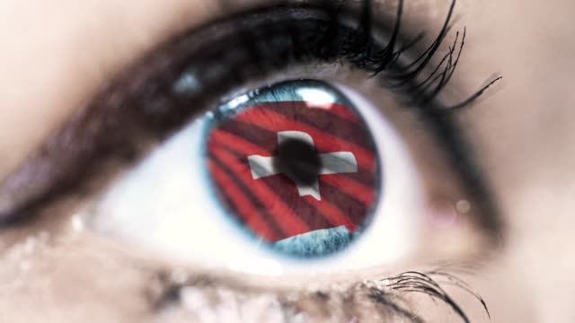 woman-blue-eye-in-close-up-with-the-flag-of-switzerland-in-iris-with-wind-motion.-video-concept