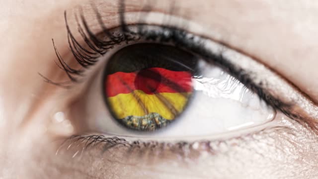 mujer-ojo-verde-en-primer-plano-con-la-bandera-de-Alemania-en-el-iris-con-el-movimiento-del-viento.-concepto-de-vídeo