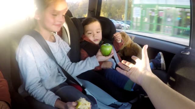 POV-von-Mutter-geben-Äpfel-an-Kinder-während-der-Autofahrt