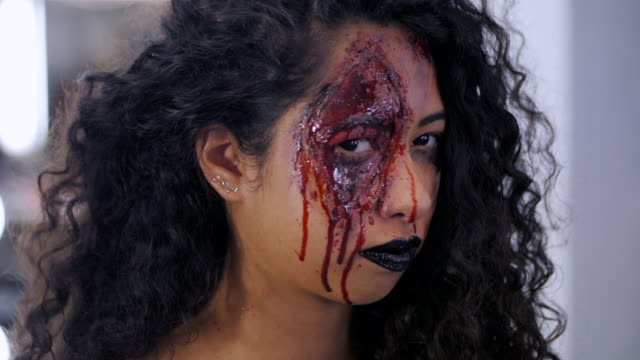 Beängstigend-Porträt-des-jungen-Mädchens-mit-Halloween-Blut-Make-up.-Schöne-Latin-Frau-mit-lockigem-Haar-Blick-in-die-Kamera.-Slow-motion