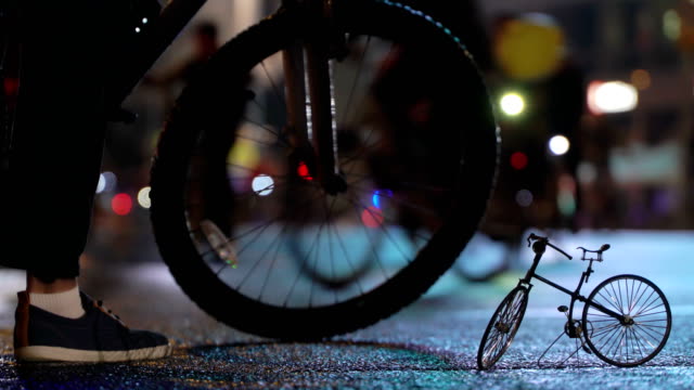 Viele-Radfahrer-fahren-nachts-Radfahren-Fahrrad-Parade-in-Unschärfe-durch-die-beleuchtete-Nacht-Stadtstraße-Hintergrund-des-kleinen-Modells-Fahrrad.-Menschenmenge-am-Fahrrad.-Radverkehr.-Konzept-Sport-gesunde-Lebensweise.-Hell-leuchtende-Lichter.-Niedrigen-Winkel