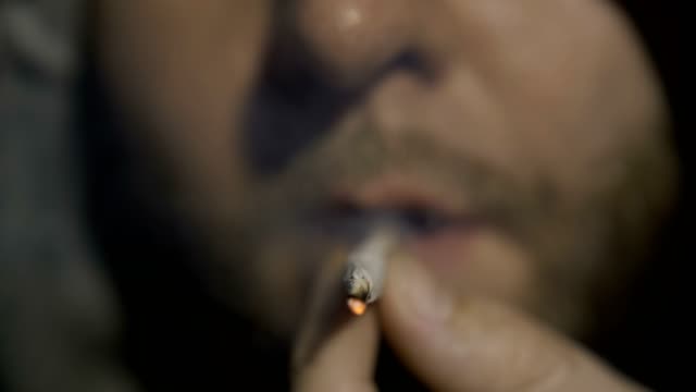 Extreme-close-up-of-man-smoking-marijuana-joint