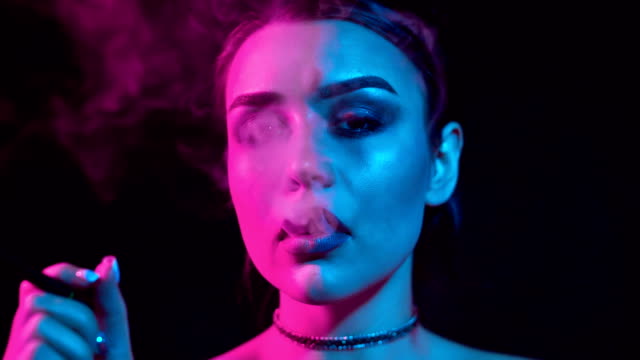 Hermosa-mujer-morena-fumar-cigarrillo-electrónico-en-luz-de-neón-color