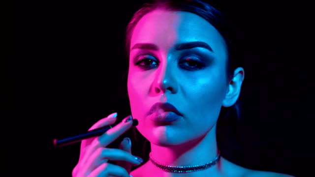 Gorgeous-brunette-woman-smoking-electronic-cigarette-in-neon-color-light