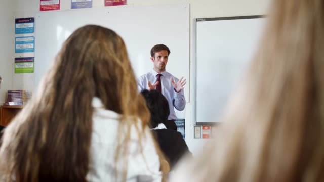 Jugendlichen-Studenten-hören-männliche-Lehrer-im-Klassenzimmer
