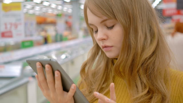 Kundin-mit-einem-digitalen-Tablet-im-Supermarkt