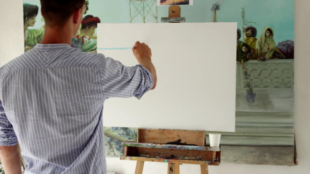 man-painter-paints-picture-on-blank-canvas
