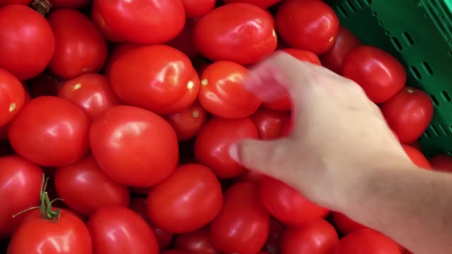Hand-eines-Mannes-Kommissionierung-frische-Tomaten-im-Supermarkt