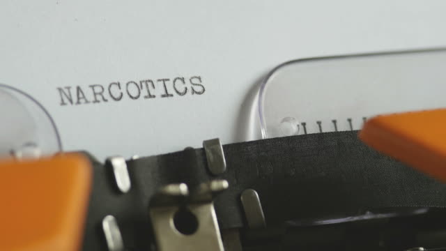 Close-up-footage-of-a-person-writing-NARCOTICS-on-an-old-typewriter