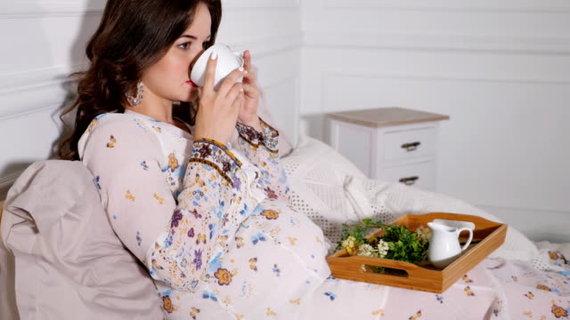 Schwangere-Frau-trinken-gesunde-Tee-im-Bett-entspannen