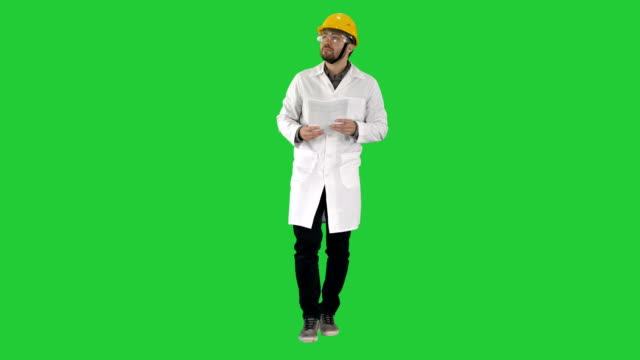 Engineer-checking-papers-and-looking-around-to-sides-on-a-Green-Screen,-Chroma-Key