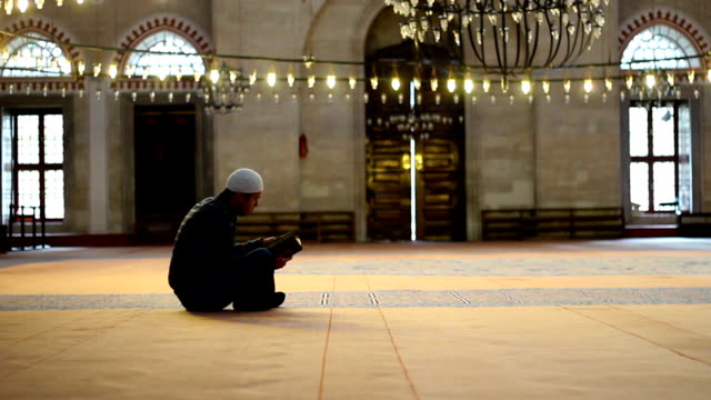 Adulto-caucásico-joven-leyendo-el-Corán-en-la-mezquita