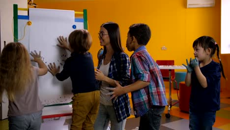 Fröhlich-diverse-Kinder-malen-Handabdrücke-auf-Klasse