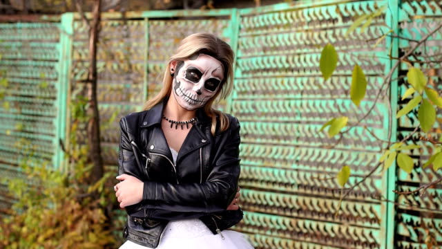 Mädchen-in-einer-Lederjacke-mit-Make-up-für-Halloween-auf-dem-Hintergrund-eines-alten-Zauns
