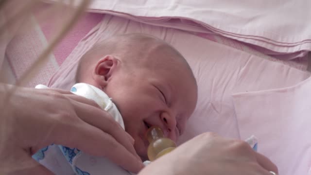 Mother-giving-bottle-with-water-to-sleepy-newborn-baby