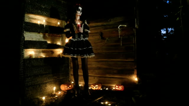 Mujer-joven-con-esqueleto-de-miedo-maquillaje-de-Halloween-sosteniendo-una-vela-encendida.-Hd