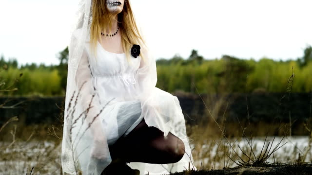 Frau-mit-Make-up-der-toten-Braut-für-Halloween-in-weißen-Hochzeitskleid-gekleidet.-4K