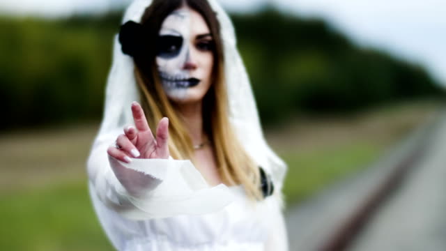 La-joven-con-maquillaje-espeluznante-para-Halloween-en-un-vestido-de-novia-blanco.-4K