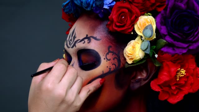Closeup-makeup-artist-draw-a-sugar-skull-pattern-on-female-model's-face.