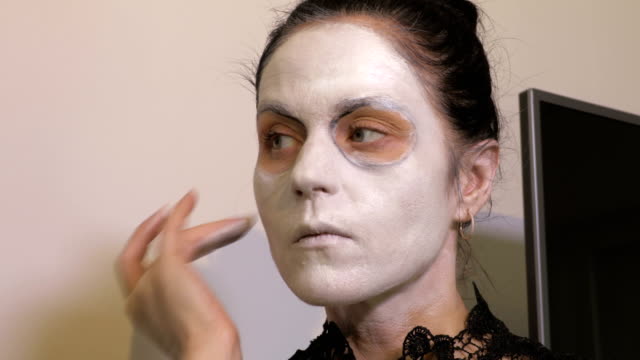 Frau-wenden-weißes-Make-up-auf-ihr-Gesicht.-Halloween-Konzept