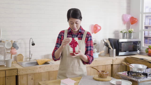 asian-woman-opening-gift-box-in-kitchen
