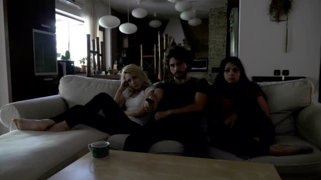 Drei-Freunde,-die-traurigen-Film-im-Wohnzimmer-auf-einer-Couch-sitzend