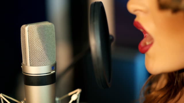 Young-woman-recording-a-song-in-a-professional-studio.