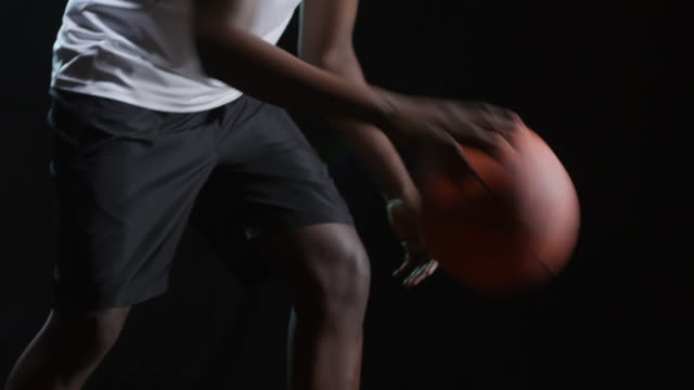 Schwarzer-Athlet-Dribbling-Basketball-auf-schwarzem-Hintergrund