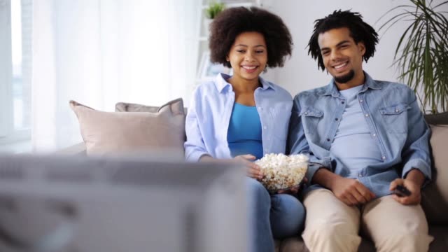 lächelnde-Paar-mit-Popcorn-zu-Hause-vor-dem-Fernseher