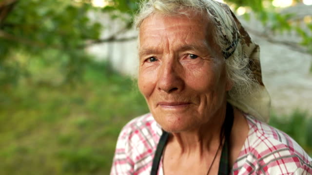 Dinámico-retrato-de-una-mujer-de-80-año-de-edad-muy-antigua-trabajando-en-el-jardín.-Primer-plano---manos-arrugadas-añadir-hierba-seca-a-una-bolsa-de-lona