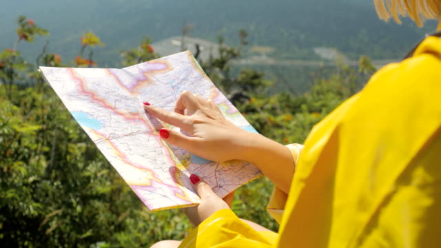 Wanderer-in-einem-gelben-Regenmantel,-Blick-auf-Karte-von-Berg.-Frau-mit-Karte-in-Bergen-FullHD
