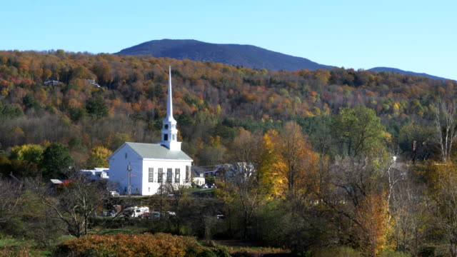 Iglesia-de-Nueva-Inglaterra-blanco-clásico-en-stowe-y-colina-con-follaje-de-otoño