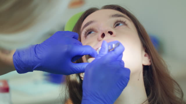 Zahnärztin-nimmt-Baumwolle-Tampon-von-Patienten-Mund-offen
