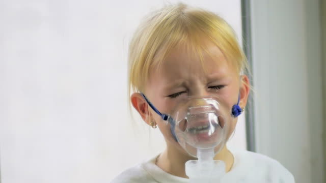 Vier-jährigen-Mädchen-in-einer-Maske-Atemgas-durch-einen-Inhalator-im-Krankenhaus-in-Zeitlupe.