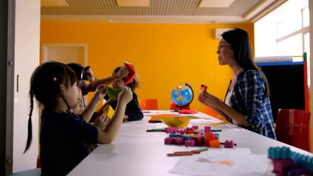 Fröhliche-Kinder-mit-handgeschöpftem-Papierspielzeug-spielen