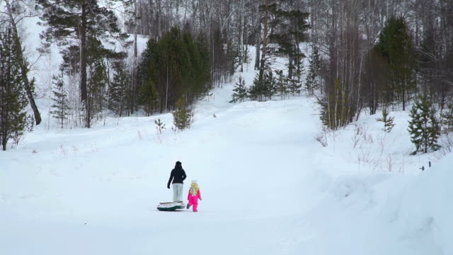 Frau-und-das-Mädchen-klettern-einen-Hügel-mit-Snow-Tube