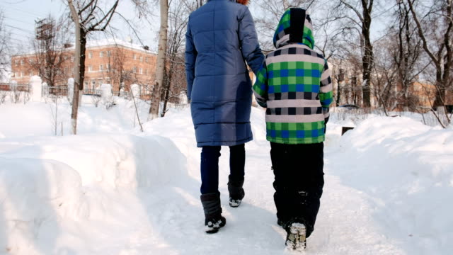 Mom-and-son-walking-in-the-winter-city-park.