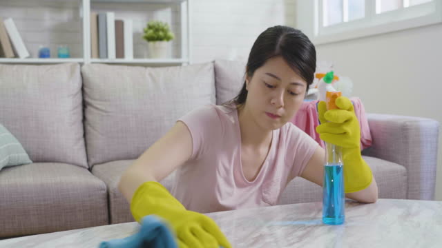 Unglückliche-asiatische-koreanische-Hausfrau-poliert-Tisch