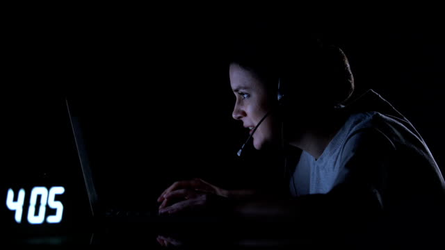Female-gamer-in-headset-playing-video-games-late-at-night,-computer-addiction