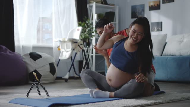 Man-and-pregnant-woman-watching-video-during-workout