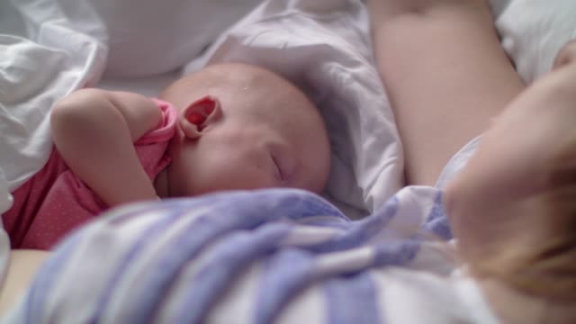 Mujer-breasfteeding-bebé-acostado-en-la-cama
