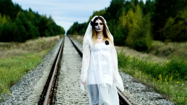 Die-junge-Frau-mit-Make-up-der-toten-Braut-für-Halloween-auf-dem-Bahngleis.-4K