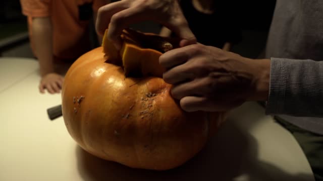 Happy-halloween.-Father-and-sons-carving-pumpkin-on-the-table-in-the-home.-Family-preparing-for-holiday.-Top-view.-Close-up