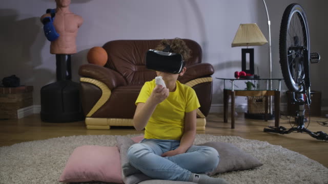 Kleiner-Junge-in-VR-Googles-bewegen-Hand-mit-Fernbedienung-und-Blick-auf-die-Richtung-des-Controllers.-Kaukasisches-Kind-in-Freizeitkleidung-mit-Augmented-Reality-drinnen.-Kino-4k-ProRes-HQ.