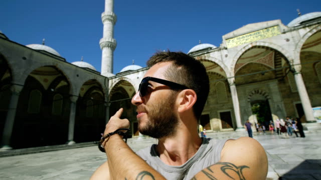 Mano-del-hombre-de-turista-feliz-tener-chat-de-vídeo-en-línea-usando-su-smartphone-cámara-junto-a-la-famosa-mezquita-azul-en-Estambul