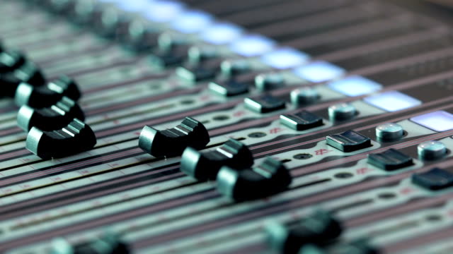 audio-mixer-in-a-studio,-the-automatic-knobs-moving-up-on-console.-Close-up-DOF