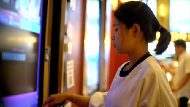 Young-Asian-Woman-using-tickets-machine-in-cinema
