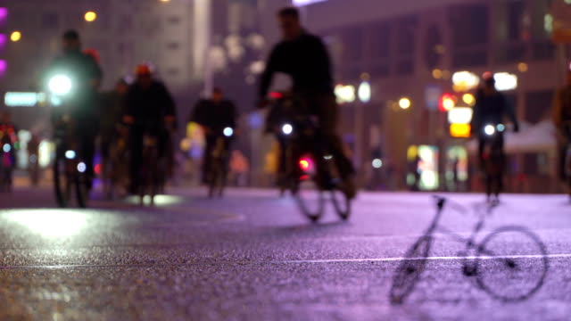Viele-Radfahrer-fahren-nachts-Radfahren-Fahrrad-Parade-in-Unschärfe-durch-die-beleuchtete-Nacht-Stadtstraße-Hintergrund-des-kleinen-Modells-der-Fahrrad-Timalapse.-Menschenmenge-am-Fahrrad.-Radverkehr.-Konzept-Sport-gesunde-Lebensweise.-Hell-leuchtende-Lichter.-Low